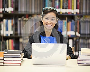 Asian woman in library with laptop