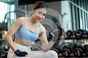 Asian woman lifting weights with equipment in the background