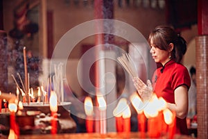 An Asian woman lighting incense sticks to pay homage to the Chinese New Year