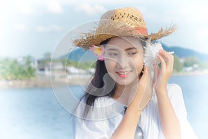 Asian woman listening sea with seashell