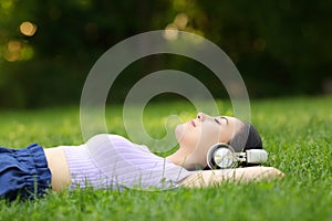 Asian woman listening to music relaxing on the grass