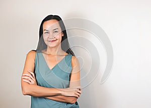 Asian woman with long back hair wearing green sleeveless blouse, smiiling and looking at camera on white background