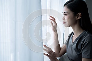 Asian woman looked out of the window, She is lonely and she wants to go outside the house