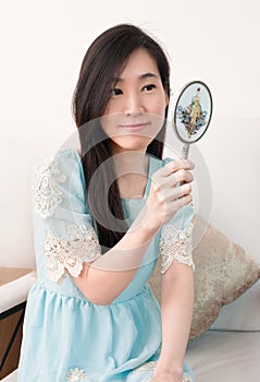 Asian woman looking in classical vintage silver mirror