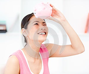 Asian woman looking through an empty piggy bank