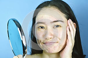 Asian woman looking at herself in the mirror, Female feeling annoy about her reflection appearance show the aging facial.