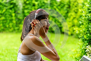 Asian woman looking on laptop relaxing after a workout in her house with a green garden in the background