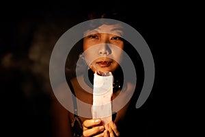 Asian Woman Looks At A Candle Extinguished In Dark.