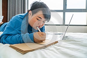 Asian woman lying on bed and writing diary