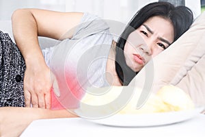 Asian woman lying down after eating cause discomfort, indigestion with stomach acid or GERD