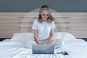 Asian woman lying down and smiling the bed and laptop