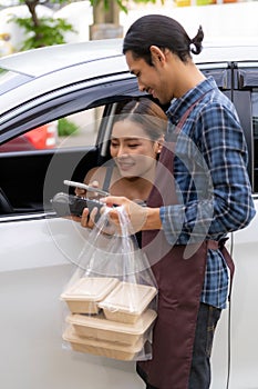 Asian woman making contactless payment with credit card for take out drive thru food