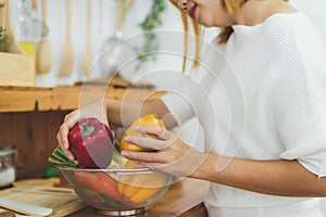 Asian woman making healthy food standing happy smiling in kitchen preparing salad.