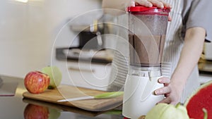 Asian woman making smoothie juice with blender in modern kitchen at home. female using tablet searching recipe from internet via w
