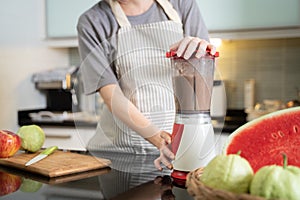 Asian woman making smoothie juice with blender in modern kitchen at home. female using tablet searching recipe from internet via w