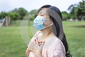 Asian woman in mask and  feels unhealthy put hand where is lungs, suffering from repeated coughing and breath difficulties