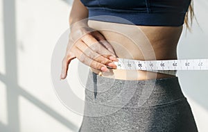 Asian woman measuring waist size