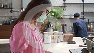 Asian woman in medical face mask looking at coffee menu in cafe. female buying drinks at cashier. shopping during covod-19 and cor