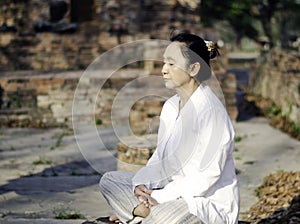 Asian woman meditating in ancient buddhist temple