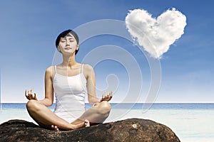 Asian woman meditating at beach