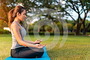 Asian woman meditating and sit in the lotus pose at park, Healthy and Yoga Concept,Mind-body improvements concept, Selective focus