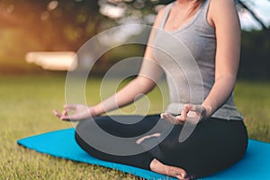 Asian woman meditating and sit in the lotus pose at park, Healthy and Yoga Concept,Mind-body improvements concept, Selective focus