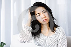 Asian woman with messy hair having problem with dandruff hand itching her dry skin on head