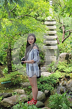 Asian Woman Model Stands Near Sculpture in Forest