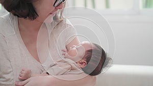 Asian woman mother embracing baby on body looking at infant with love emotion. female parent holding and talking to sleeping daugh