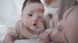 Asian woman mother parent playing with baby infant crawling under blanket. happy kid learning lesson development skill.