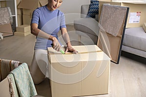 Asian woman moving into new apartment with cardboard boxes