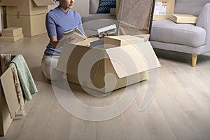 Asian woman moving into new house holding and unpacking her belongings with cardboard boxes