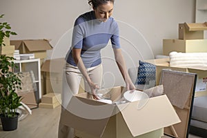 Asian woman moving into new house unpacking her belongings with cardboard boxes