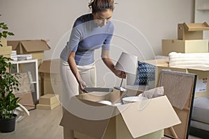 Asian woman moving into new house unpacking her belongings with cardboard boxes