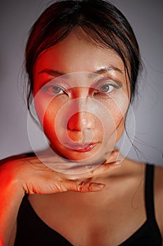 Asian woman in neon colorful bright lights posing in studio, portrait of a beautiful sexy girl with trendy makeup