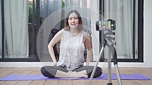 Asian woman online instructor yoga demonstration the pose to audience via mobile smart phone tripod live streaming. female work ou