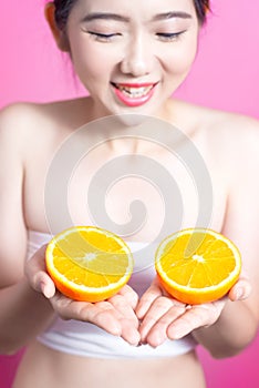 Asian woman with orange concept. She smiling and holding orange. Beauty face and natural makeup. Isolated over pink background.
