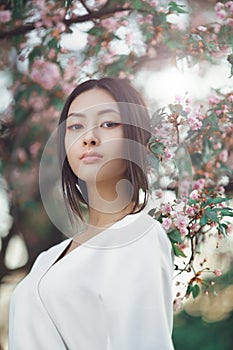 Asian woman outdoors on spring against flower blossom