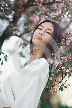 Asian woman outdoors on spring against flower blossom