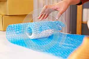 Asian woman packing a vase with air bubble wrap for a fragile product before sending in the parcel. Ready to send to a customer