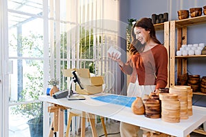 Asian woman packing a vase with air bubble wrap for a fragile product before sending in the parcel. Ready to send to a customer