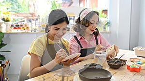 Asian woman painting on her handicraft ceramic at pottery workshop