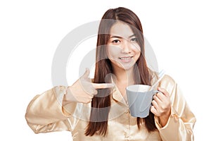 Asian woman in pajamas point to toothbrush in mug