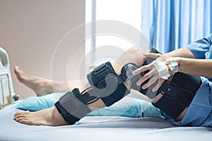 Asian woman patient with bandage compression knee brace support injury on the bed in nursing hospital.healthcare and medical