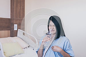 Asian woman patient having or symptomatic reflux acids at hospital,Gastroesophageal reflux disease,Drinking water