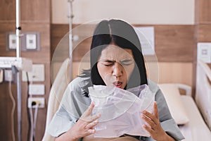 Asian woman patient puke or vomiting into plastic bag at hospital,Nausea,Indigestible