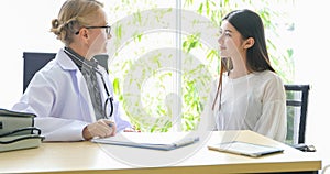 Asian woman patient sitting with doctor about her illness and showing x-ray results with blood pressure and heart rate measurement