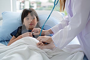 Asian woman pediatrician doctor hold stethoscope for exam a little girl patient and heck heart lungs of kid, Good family doctor