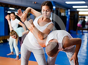 Asian woman performing elbow strike and wristlock to male opponent during self defence training