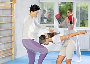 Asian woman performing knee strike to sparring partner face during self-defense training